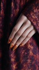 Delicately poised hand with marbled autumn hues, ethnic Eurasian femme, invoking Samhain mystique, bespoke heritage textiles enveloped