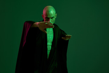 Intense man posing with a powerful stance, dressed in flowing black fabric, showcasing an athletic...