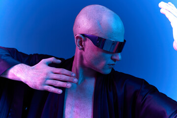 Futuristic man in stylish sunglasses striking a dynamic pose, bathed in vibrant blue and purple...