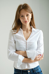 Teenager with long hair poses confidently in a stylish outfit indoors against a neutral background