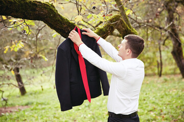 A man is hanging a jacket on a tree branch