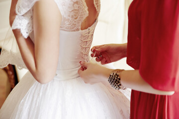 A woman in a white dress is getting her dress altered by another woman