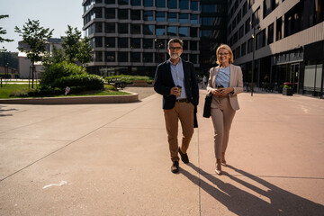 Mature business professionals walking to office in modern urban district