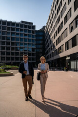Confident mature businessman and woman commuting to work in city center