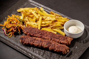 details of tasty meat kebabs with salad and fries