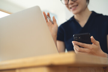 Smiling business woman talking through video call on laptop, remote working at coffee shop. Woman doing video chat calling to colleague during working with laptop computer on table at home office