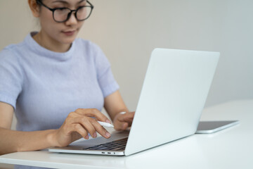 Woman hand typing on laptop computer keyboard on office table at home. Asian casual business woman...