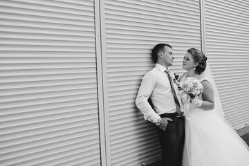 A bride and groom are posing for a picture in front of a wall
