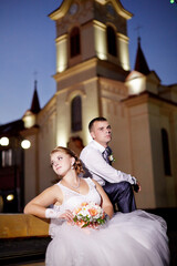 A bride and groom are posing for a picture in front of a church