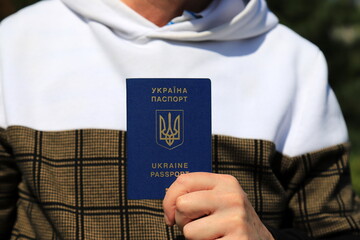 Man holds in hands passport with inscription in Ukrainian - Passport of Ukraine and state emblem of...