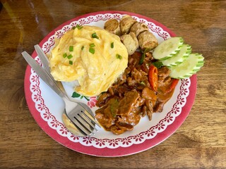 Thai Beef curry (Panaeng neua) serving with omlette,  deep fried chicken rolls and rice. Thai food. Selective focus, top view