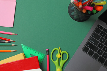 Top view of school supplies, pencils, erasers, paper clips and notebooks, on a green background....