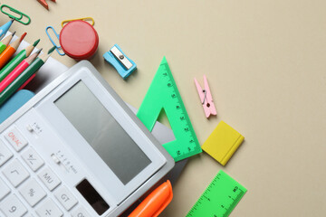Top view of school supplies, pencils, erasers, paper clips and notebooks, on a beige background....
