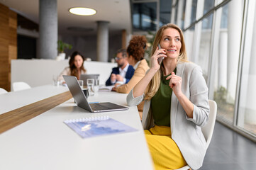 Female professional discussing over phone call while working online on computer in meeting room...