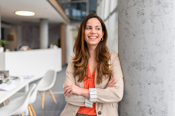 Portrait of successful entrepreneur with arms crossed looking away thoughtfully and leaning on...