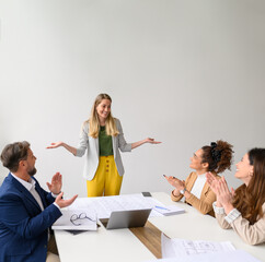 Happy business people applauding for female architect and celebrating her success in office during...