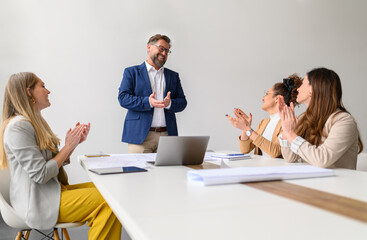 Happy business professionals applauding for male architect and celebrating his success in office...