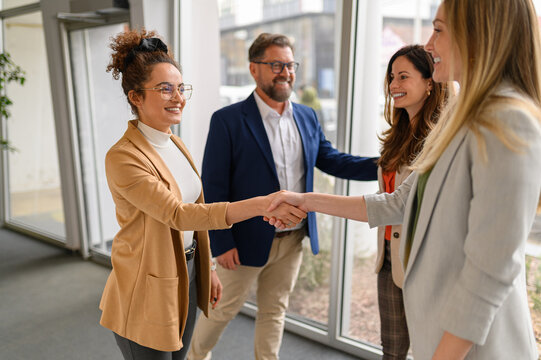 Team of professionals exchanging handshakes and greetings in office during a business meeting or collaboration - Powered by Adobe