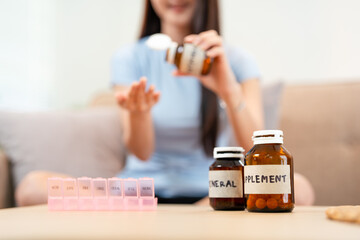 Woman taking out pills from bottle. Healthy woman sitting in living room with pills takes vitamins...