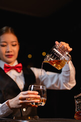 Professional female bartender preparing alcoholic drinks in a bar