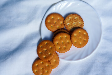 Round crackers stacked on white plate over fabric background