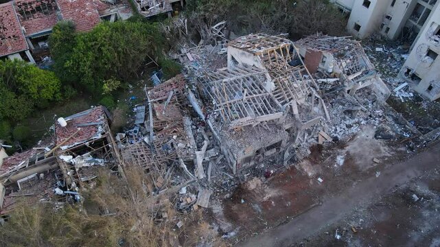 Drone footage from above shows a fully collapsed residential home in northern Tel Aviv after a missile impact. Structural remnants and rubble cover the area.