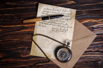 Vintage pocket watch with handwritten letter and pen on wooden surface
