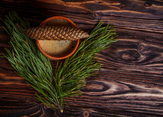 Cup of coffee with pine cone and evergreen branch on wooden table