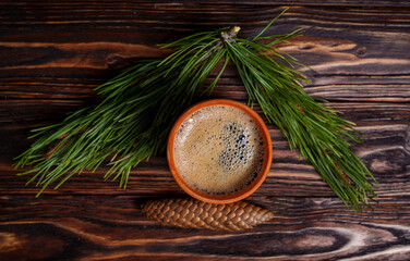 Cup of coffee with pine cone and evergreen branch on wooden table