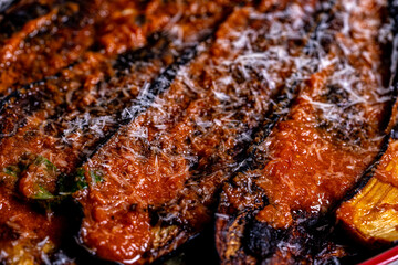 Italian cuisine: delicious macro Melanzane alla parmigiana in a baking dish. Background for using the menu
