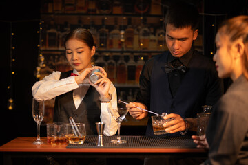 Professional female bartender preparing alcoholic drinks in a bar