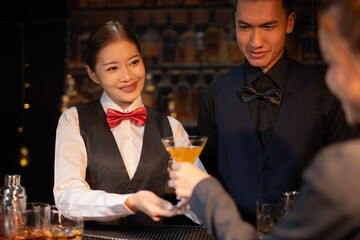 Professional female bartender preparing alcoholic drinks in a bar