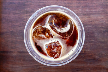 top view, cola with ice or iced americano or ice lemon or ice tea in plastic cup on wooden background.