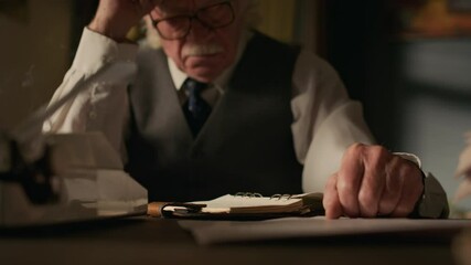 Closeup shot of hands of senior Caucasian man writing down notes sitting at desk and working in study room - Powered by Adobe