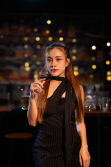 Beautiful young woman drinking alcohol at nightclub bar enjoying a pub party