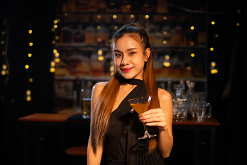 Beautiful young woman drinking alcohol at nightclub bar enjoying a pub party