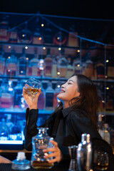 Beautiful young woman drinking alcohol at nightclub bar enjoying a pub party