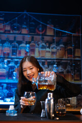Beautiful young woman drinking alcohol at nightclub bar enjoying a pub party