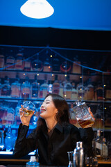 Beautiful young woman drinking alcohol at nightclub bar enjoying a pub party