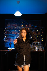 Beautiful young woman drinking alcohol at nightclub bar enjoying a pub party
