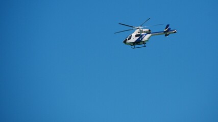 police helicopter patrols flying in blue cloudless sky