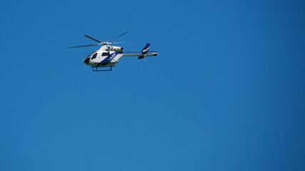 police helicopter patrols flying in blue cloudless sky