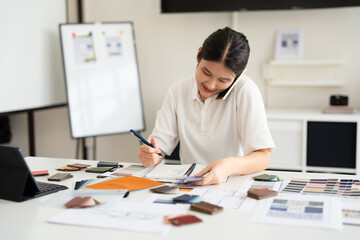 Designer working in office and making call on mobile phone.