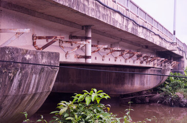 The enduring architecture of a weathered concrete bridge with rusty metal supports and green...