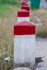 Vibrant red and white concrete bollards standing in a structured row along an outdoor pathway,...