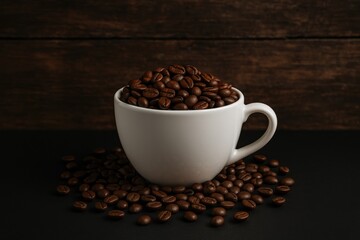 Fototapeta premium A ceramic mug brimming with roasted coffee beans placed on a dark wooden surface, evoking a fresh morning vibe