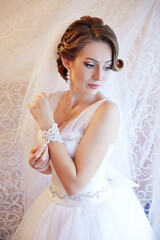 A woman in a white dress is wearing a white veil and a white bracelet
