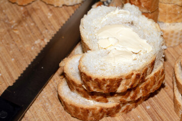 Sliced and buttered French stick baguette bread ready for dinner food prep with knife