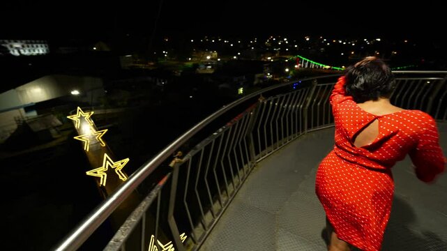 Tourist enjoying the illuminated city view from the circular viewpoint at night in Tena, Ecuador