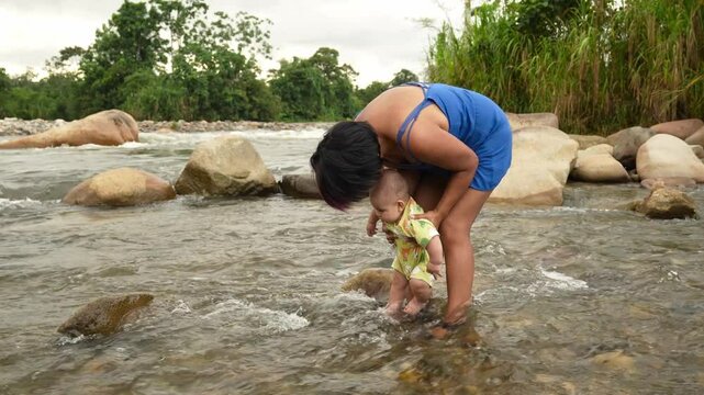 Mother gently bathes her young son in a river surrounded by natural beauty in the Amazon region of Ecuador
